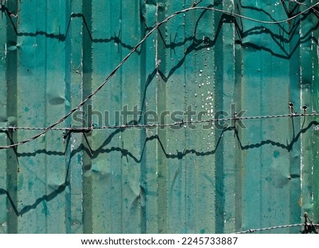 Green metallic surface and barbed wire