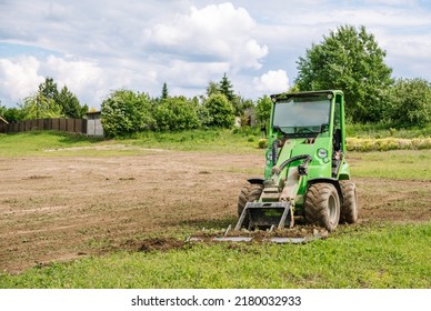 A Green Mini Skid Steer Loader Clear The Construction Site. Land Work By The Territory Improvement. Small Tractor With A Ground Leveler For Moving Soil, Turf. Machine For Agriculture Work. Copy Space.