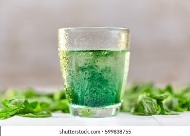 Green Mint Chlorophyll Drink In Glass With Water Drops On White Table