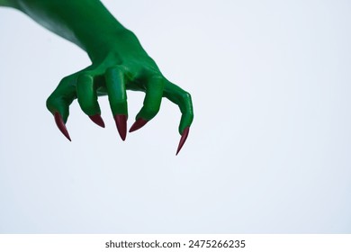 A green monster hand with long nails, isolated against a dark background, evokes horror and fear. Perfect for Halloween, this spooky image captures the essence of evil and the undead. - Powered by Shutterstock