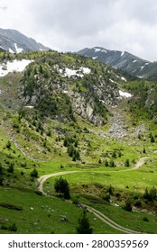 Green mountain landscape with sparse trees and distant peaks under a vibrant blue sky