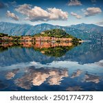 Green mountains and colorful buildings of Bellagio town reflected in the calm waters of Como lake, Italy, Europe. Gorgeous summer scene of Crocione peak. Traveling concept background.