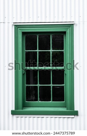 Green multi-paned window with surrounding corrugated walls
