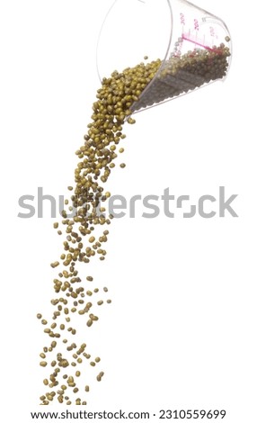 Green mung beans fall down in measured cup, green mung bean float explode, abstract cloud fly. Dried green mung beans splash throwing in Air. White background Isolated high speed shutter, freeze