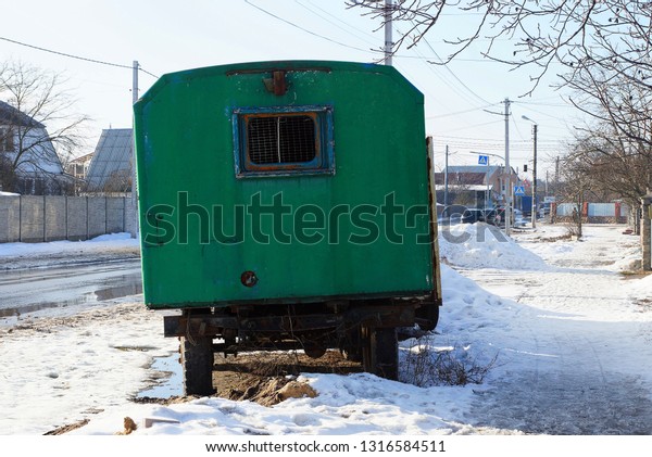 green old metal trailer booth stands on the road in\
white snow
