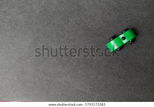 Green old wooden car toy top view on grey stone\
background. Car rental