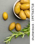 Green olives. Bella di cerignola Italian olives. Colored olives and a sprig of rosemary lie on a black stone countertop. Culinary banner or poster for advertising with place for text