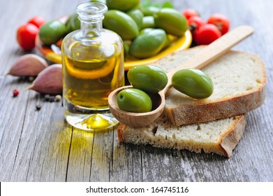 Green olives on a wooden spoon on a slice of bread - Powered by Shutterstock
