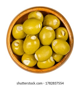 Green olives stuffed with garlic cloves in wooden bowl. Big olives, fruits of Olea europaea, hand filled with pickled garlic pieces. Closeup from above, on white background, isolated macro food photo. - Powered by Shutterstock