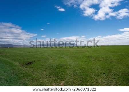 green open fields  in the country side with blue sky and mountains in distance