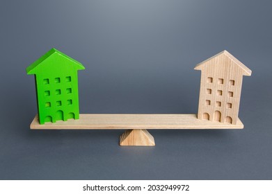 Green And Ordinary Houses Are On The Scales. Comparison Of Ecological Housing With Conventional Housing. Advantages And Disadvantages Of Energy Efficient Buildings. Net Zero Carbon Emissions