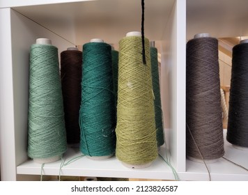 Green And Other Earth Color Thread In Cone Shaped Bobbins On Display