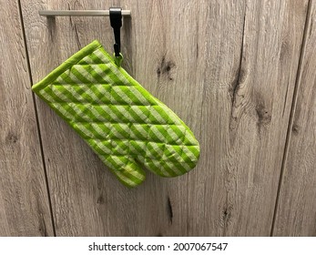 An Green Oven Mitt Hanging On The Kitchen Cabinet Doors