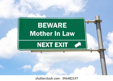 Green Overhead Road Sign With A Beware Mother In Law Next Exit Concept Against A Partly Cloudy Sky Background.