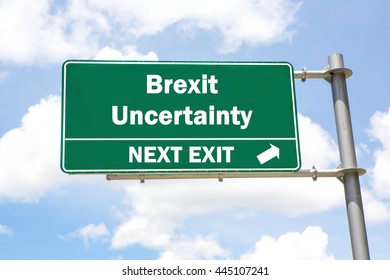 Green Overhead Road Sign With A Brexit Uncertainty Ahead Concept Against A Partly Cloudy Sky Background.