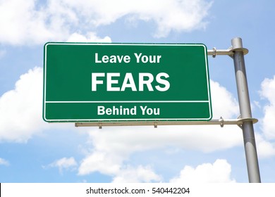 Green Overhead Road Sign With A Leave Your Fears Behind You Concept Against A Partly Cloudy Sky Background.