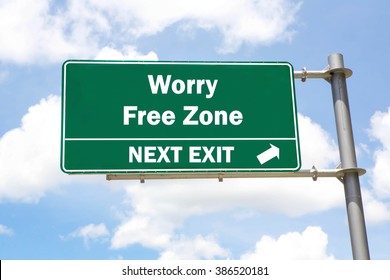 Green Overhead Road Sign With A Worry Free Zone Exit Concept Against A Partly Cloudy Sky Background.
