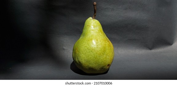 Green packham pears fruit on black background. Pears are consumed fresh, canned, as juice, and dried.