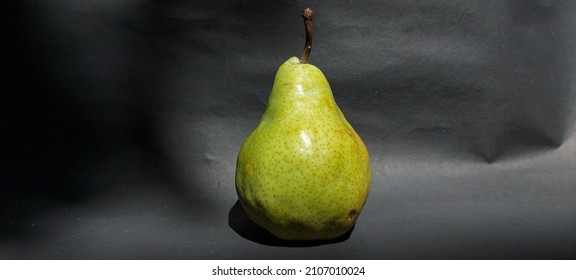 Green packham pears fruit on black background. Pears are consumed fresh, canned, as juice, and dried.