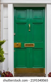 Green Painted Front Door With White Frame Surround And Brass Hardware. Sturdy External Six Panel Wooden Door On Victorian City Home UK. Brass Furniture Including Letterbox, Lick Plate, And Knocker. 