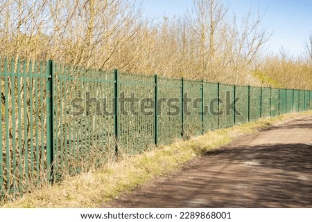 green Palisade security Fencing against a bright blue sky