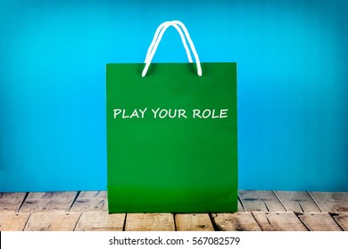 Green Paper Bag With Text Play Your Role On Blue Background.