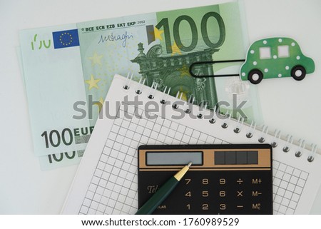 Green paper clip in the shape of a carCalculator, pen and banknotes of one hundred euros, we plan a trip by car
