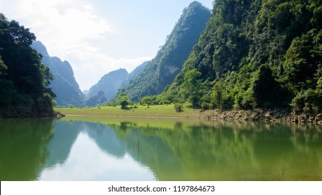 Green pasture and mountain reflection on lake - Shutterstock ID 1197864673