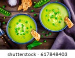 Green pea soup with croutons on wooden rustic background