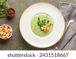 Green peas cream soup with croutons in plate. Summer vegetable food. Top view