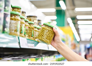 Green peas in a glass jar in the hands of a customer in a store - Shutterstock ID 2191922527