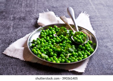 Green peas with mint in a bowl on a dark background. Selective focus.