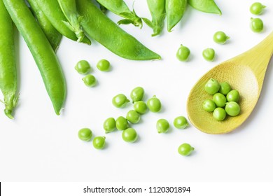 green peas in a wooden spoon close-up. pods of green peas on a white background. background with green peas.