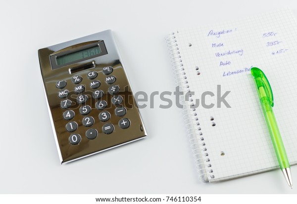 A green pen, a\
calculator and a writing pad with the German words for expenses,\
rent, car, insurance, food,