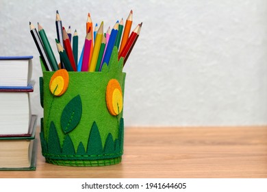 Green Pencil Holder On A Wooden Table With Books.