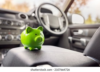 Green piggy bank money box in car interior, vehicle purchase, insurance or driving and motoring cost