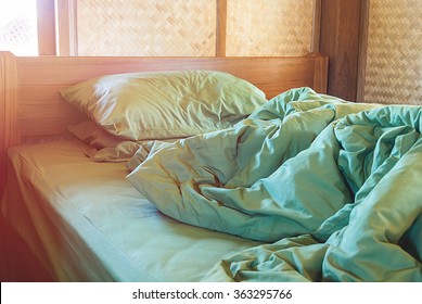 Green Pillow And Blanket With Wrinkle Messy On Bed In Vintage Wooden Bedroom With Lighting Upper Left Side, From Sleeping In A Long Night Winter.