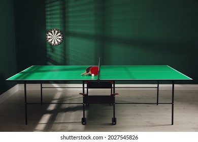 Green Ping Pong Table With Rackets And Ball Indoors