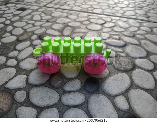 green\
and pink children\'s toy car left in the front\
yard