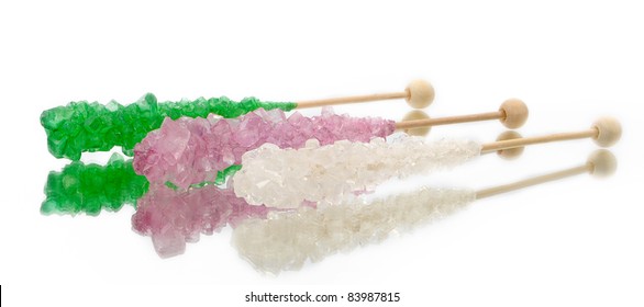 Green, Pink, And White Rock Candy With Stick On A White Background With Reflection