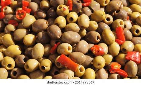 Green pitted olives with red pepper in oil, at the farmers market, preserved olives for salads, seasonal vegetables, Italy - Powered by Shutterstock