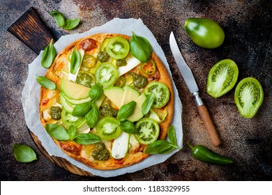 Green pizza with pesto, zucchini, tomatoes, avocado, jalapeno, mozzarella cheese and fresh basil - Powered by Shutterstock