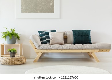 Green Plant Grey Pot On Wooden Stand Next To Scandinavian Couch With Pillows And Beige Futon