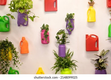 Green Plants And Flowers Growth In Recycled Colored Flower Pots Made Of Used Plastic Bottles And Canisters. Wall Filled With Hanging Pots Made With Recycled Bottle. Plastic Free. Zero Waste. Ecology 