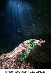 a green plastic bottle in a cave underwater ocean pollution with sun beams and rays - Shutterstock ID 2224214223