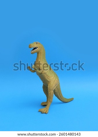 Green plastic dinosaur toy on blue background