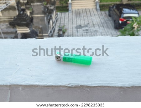 a green plastic lighter on the end of the wall