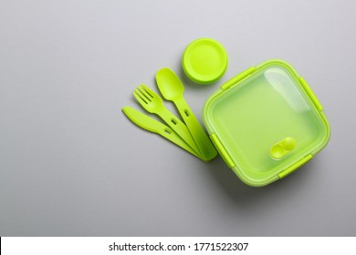 Green Plastic Lunch Box With Fork, Spoon, Knife On Green Background.Top View,flat Lay. Food Container For School And Office.Copy Space.