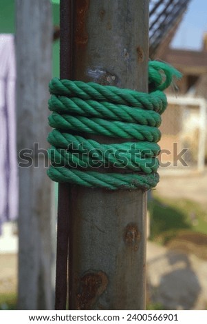 green plastic rope wrapped around an iron pole                  
