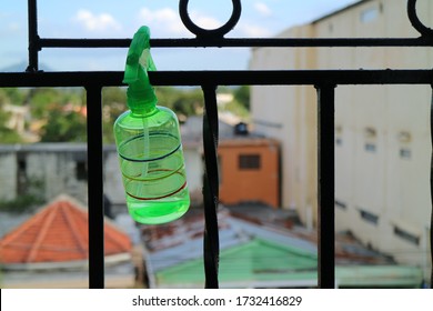 A Green Plastic Spray Bottle Hung On A Security Grill